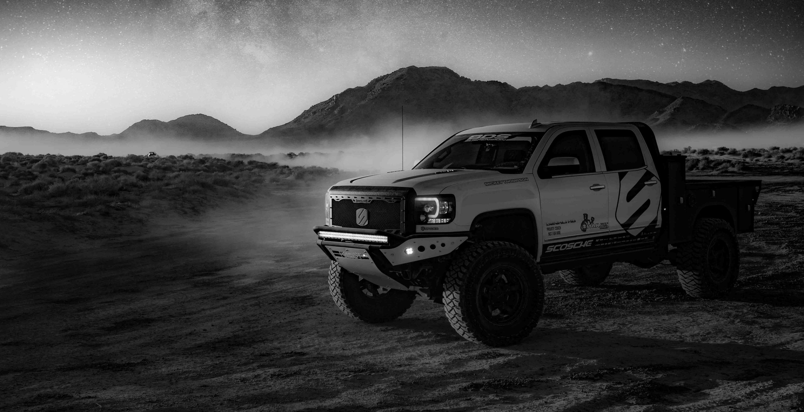 Black and white truck driving in desert